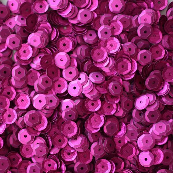 Pink pailletter 6 mm, 500 stk., skinnende runde palietter spredt foran en skål.