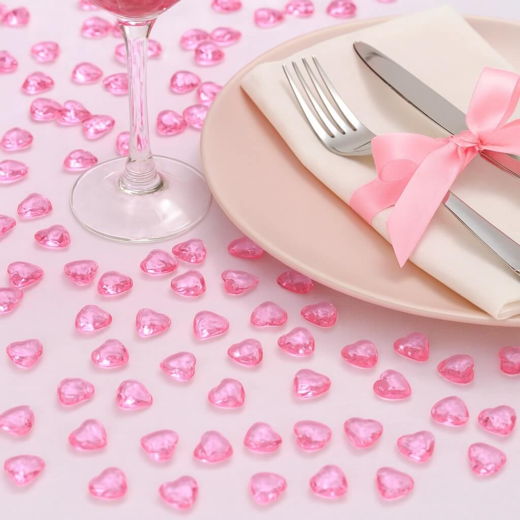 Lyserøde hjerteformede pynte diamanter spredt på en lyserød baggrund.