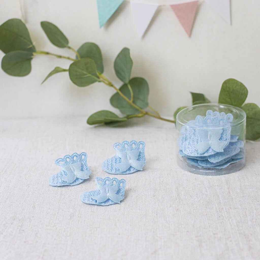 Små lyseblå dekorative sokker som barnedåbspynt på pyntet festbord