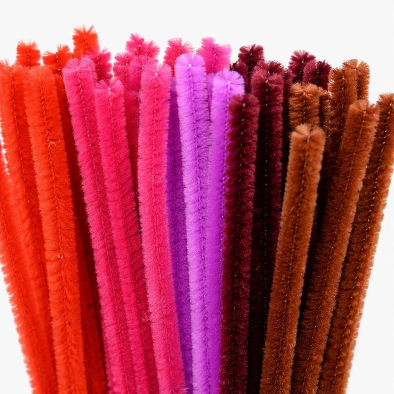 Close-up af chenille piberensere i rød mix med røde, pink, lilla og brune nuancer. Bløde hobby piberensere 6 mm til kreative projekter.